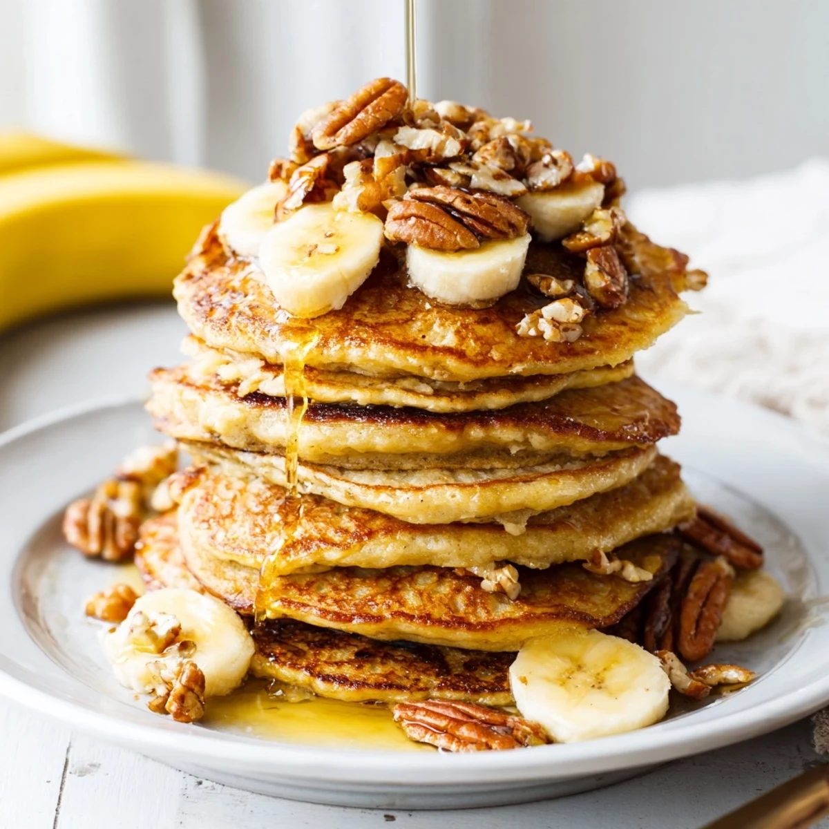 Homemade golden-brown banana pancakes with drizzles of maple syrup ready for the best brunch.
