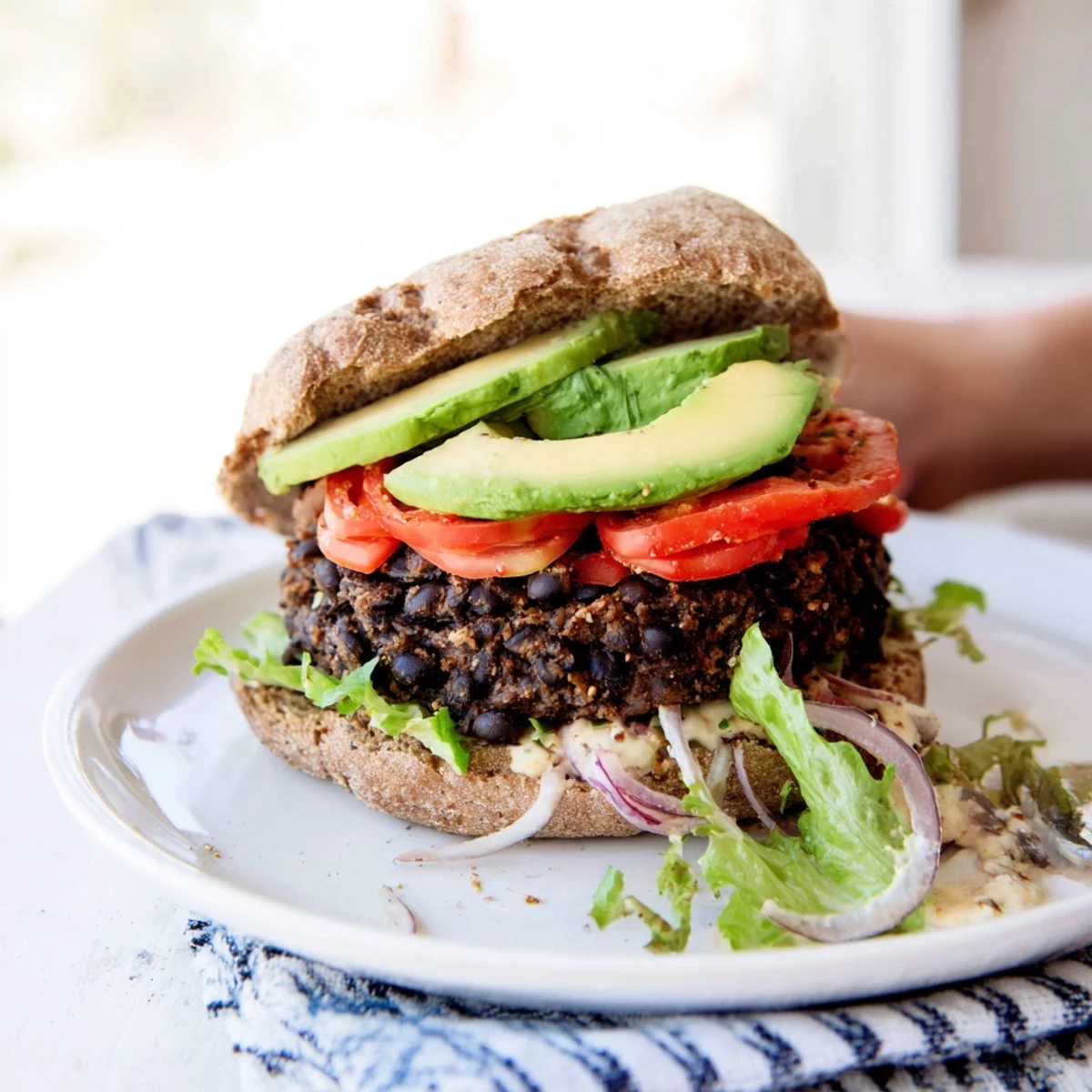 A complete Zesty Black Bean Burger with a juicy patty, ripe avocado and crunchy toppings, ready to eat.