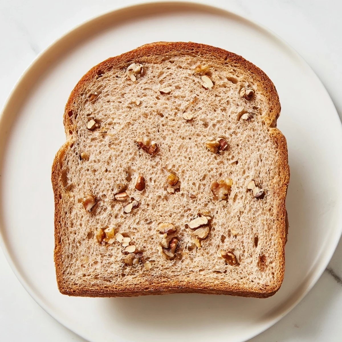 Beautifully browned Nutty Whole Wheat Loaf Bread with a scattering of toasted nuts on top.