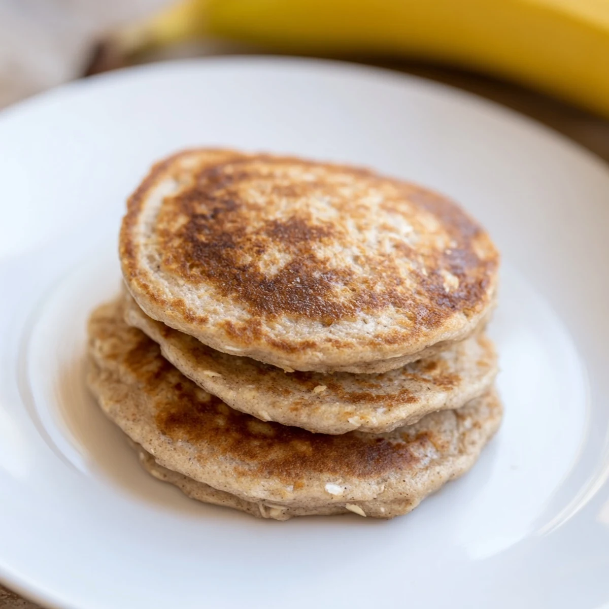 Golden-brown Banana Oat Pancakes stacked with fresh fruit, a healthy and delicious breakfast choice.
