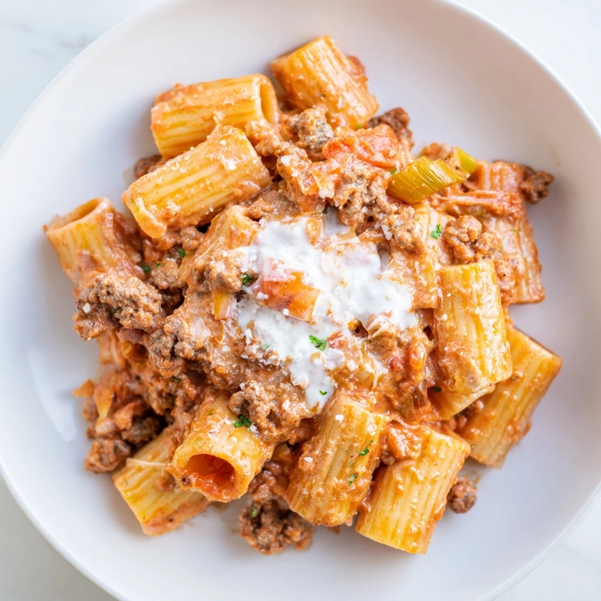A steaming bowl of Kimchi Ragu Pasta, with rigatoni coated in a rich, red sauce.