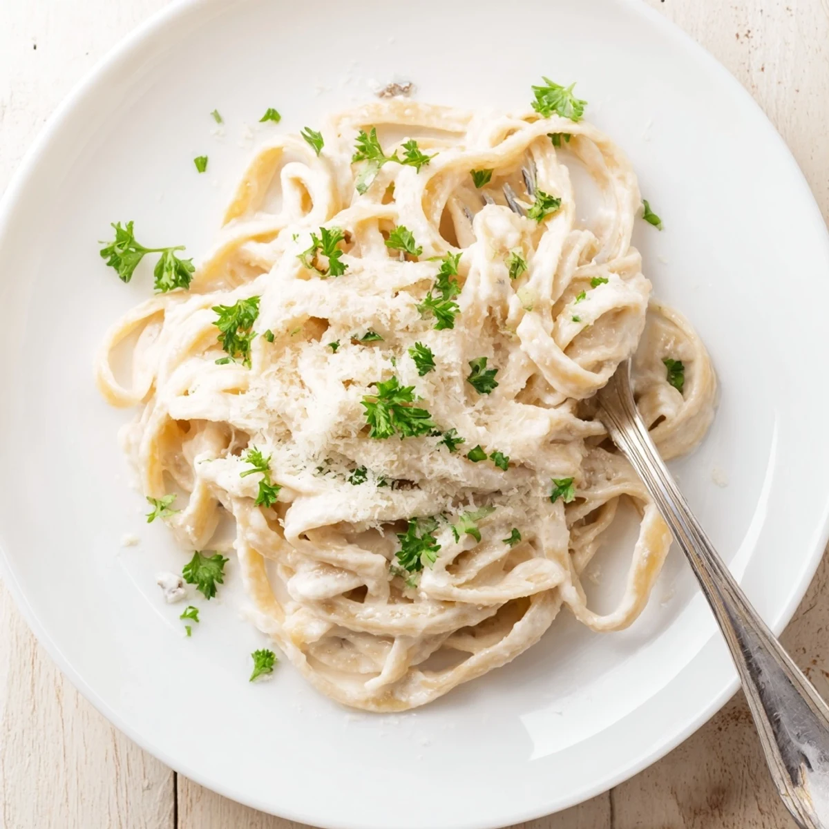 A close-up of Easy Creamy Cauliflower Alfredo fettuccine twirled on a fork, showcasing the velvety, dairy-free sauce clinging to the pasta strands.  