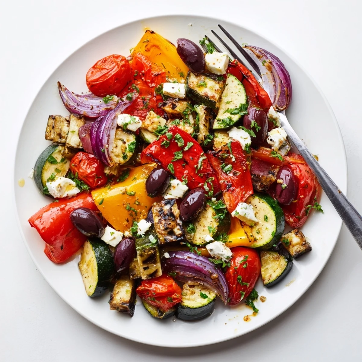 Vibrant roasted vegetables like bell peppers and zucchini are tossed with feta, olives, and parsley in a warm Roasted Greek Salad.