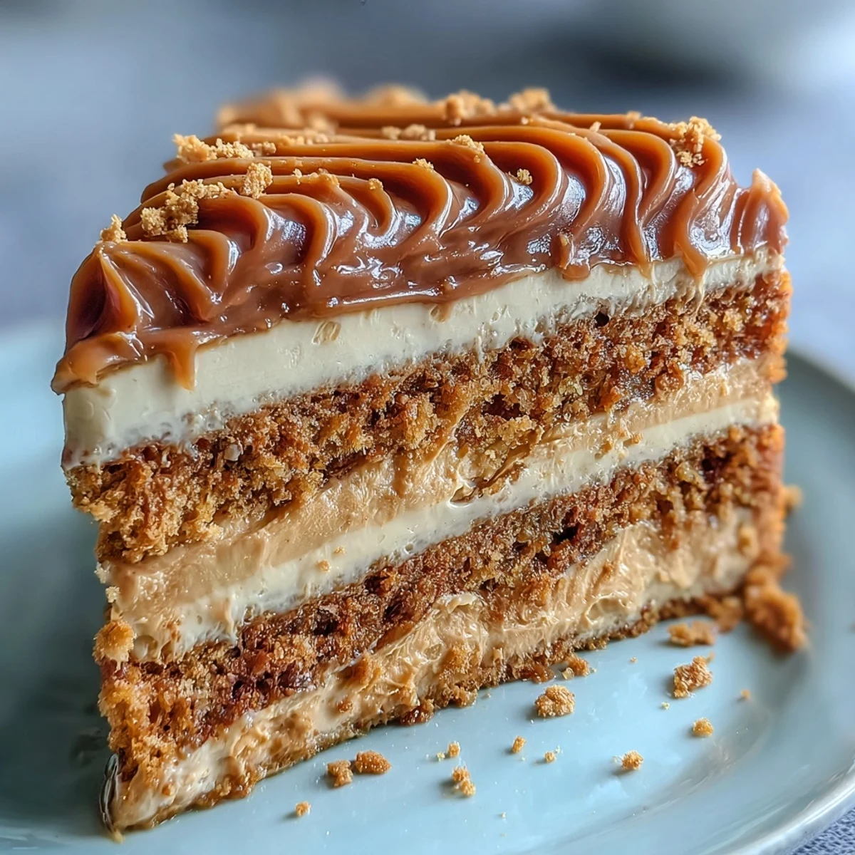 Decadent Baked Biscoff Cake with Creamy Lotus Frosting garnished with cookie crumbs on a rustic board.
