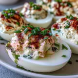 Million Dollar Deviled Eggs stacked on a serving platter, creamy yolk filling with chives and a dusting of paprika.