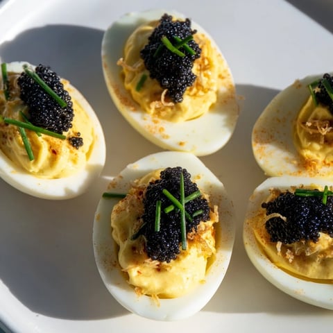 Elegant deviled eggs topped with glistening caviar and crunchy shallots, a perfect appetizer.