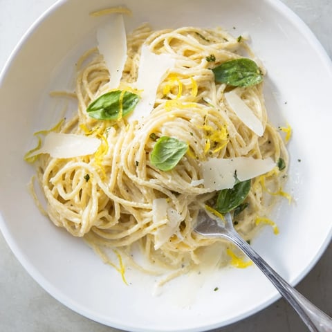 Golden spaghetti coated in a creamy ricotta and bright lemon sauce, garnished with fresh basil and extra Parmesan cheese.