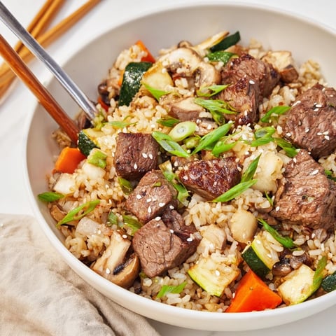 Golden-brown steak cubes, vibrant zucchini, and fluffy jasmine rice tossed in a skillet for an easy hibachi steak with fried rice dinner.