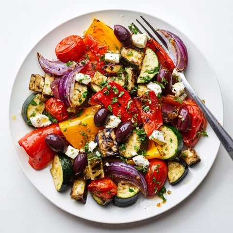 Vibrant roasted vegetables like bell peppers and zucchini are tossed with feta, olives, and parsley in a warm Roasted Greek Salad.