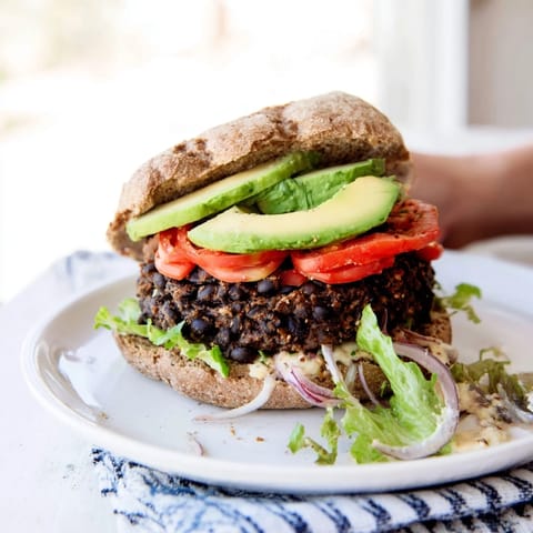 A complete Zesty Black Bean Burger with a juicy patty, ripe avocado and crunchy toppings, ready to eat.