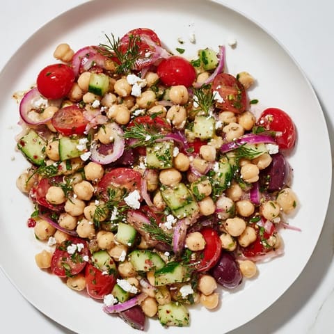 A colorful bowl of Dense Bean Salad, featuring mixed beans and chopped vegetables, drizzled with dressing.