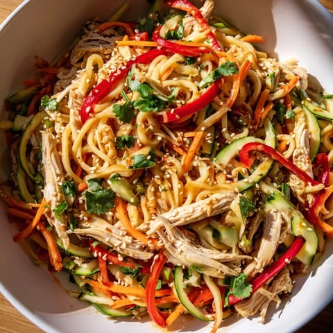 A close-up shot of Chilled Chicken Noodle Salad features a delicious sesame dressing glistening over ingredients.