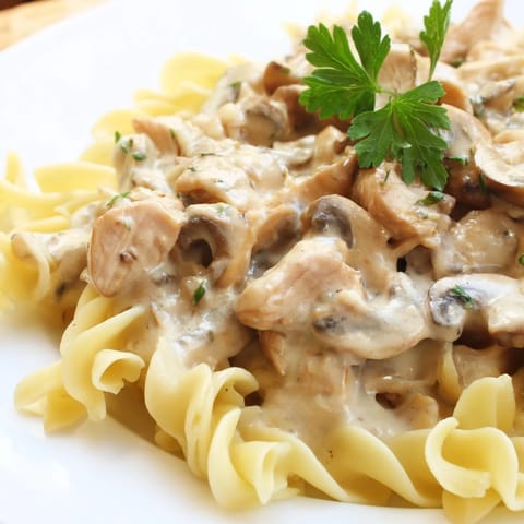 Hearty Chicken and Mushroom Stroganoff served steaming hot with tender noodles and fresh parsley garnish.