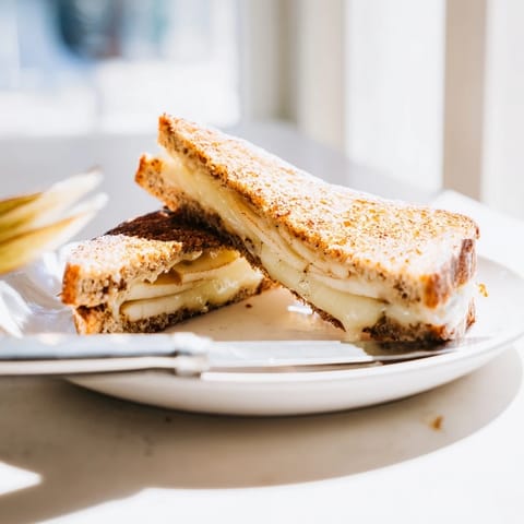 Golden-brown smoked Gouda and apple grilled cheese slices ooze melted cheese, served on a rustic plate.