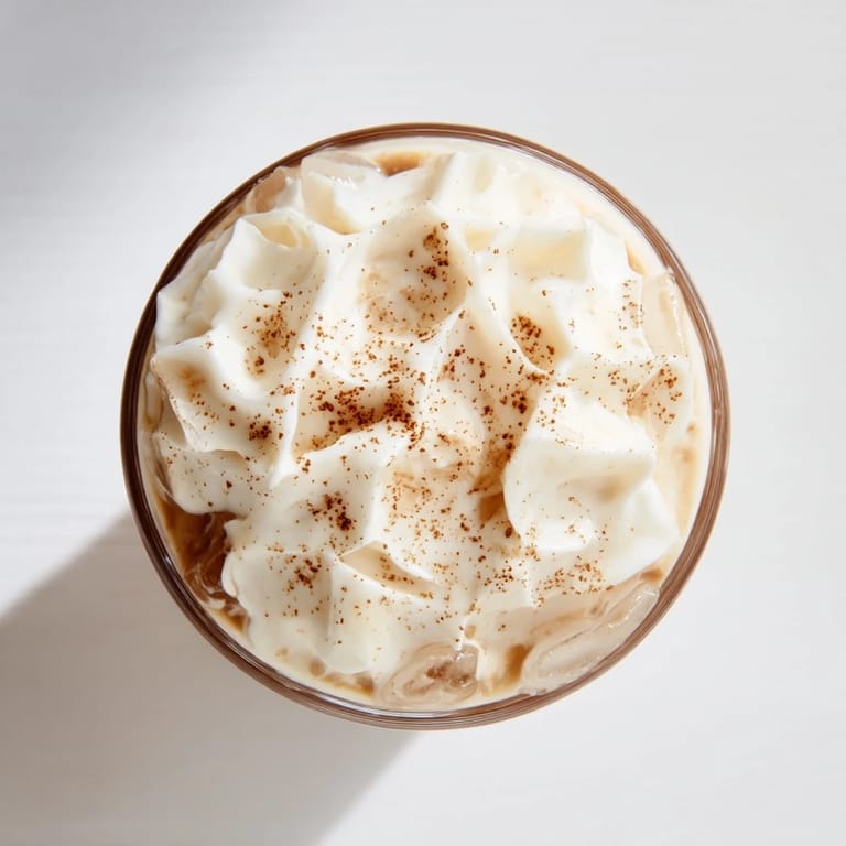 Spoonful of fluffy whipped Dalgona coffee melting into cold milk, offering a frothy, sweet sip for coffee lovers.
