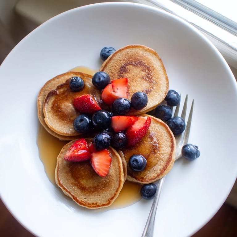 Freshly cooked Banana Pancakes served on a plate with a dollop of Greek yogurt and chopped nuts.
