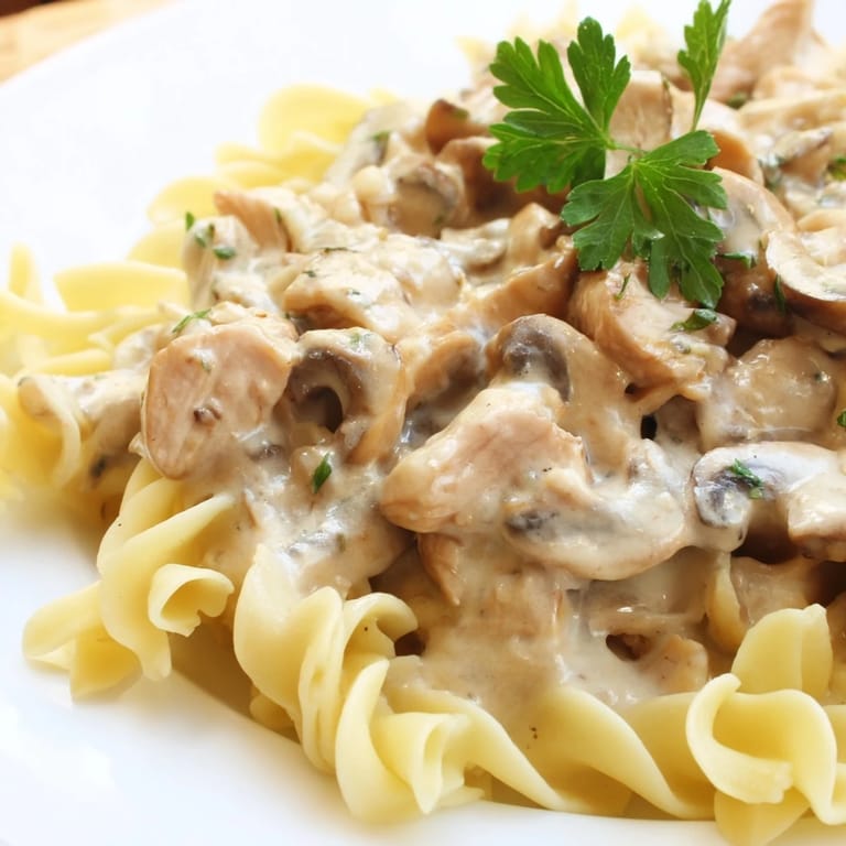 Hearty Chicken and Mushroom Stroganoff served steaming hot with tender noodles and fresh parsley garnish.