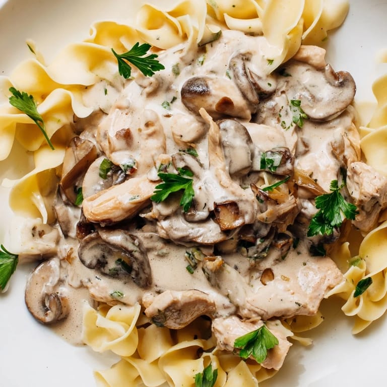 A comforting bowl of Chicken and Mushroom Stroganoff features succulent chicken, earthy mushrooms, and rich sour cream sauce.