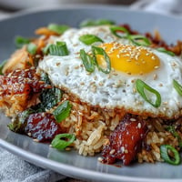Kimchi cabbage fried rice with tangy kimchi, crisp vegetables, and a fried egg, served in a rustic bowl.  